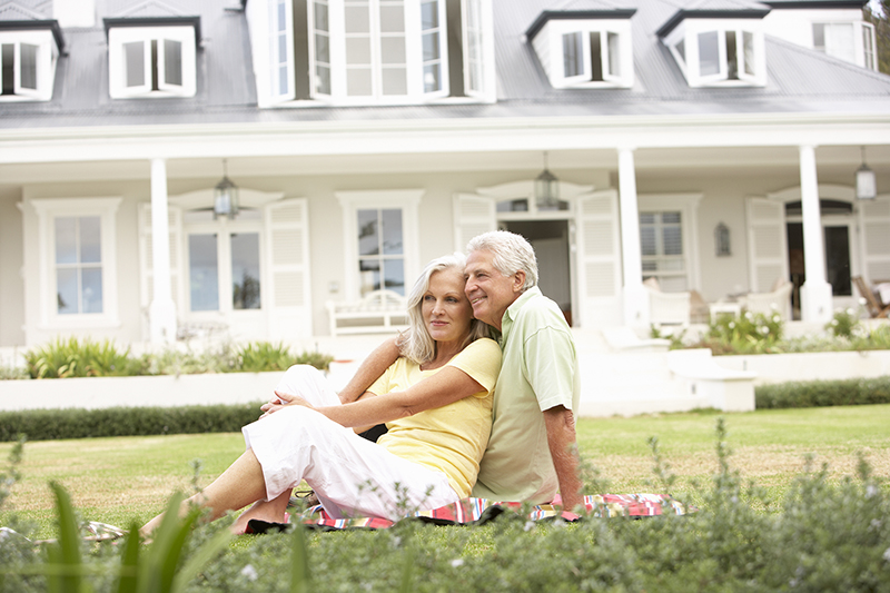 Extended Family Group Sitting Outside House On Lawn